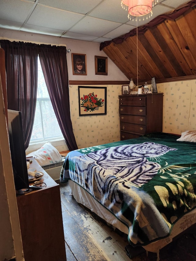 bedroom with wallpapered walls, hardwood / wood-style floors, and lofted ceiling