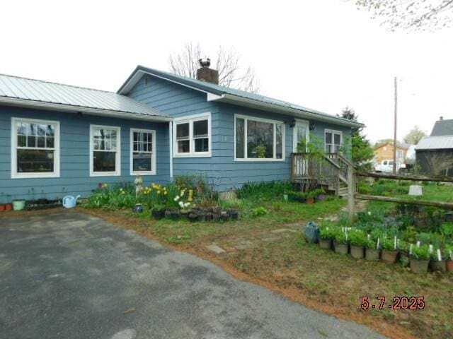 single story home with a chimney and metal roof