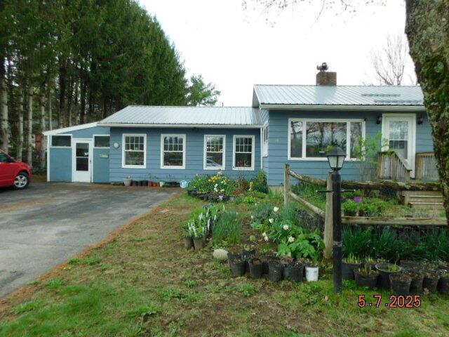 single story home with a chimney, metal roof, and driveway