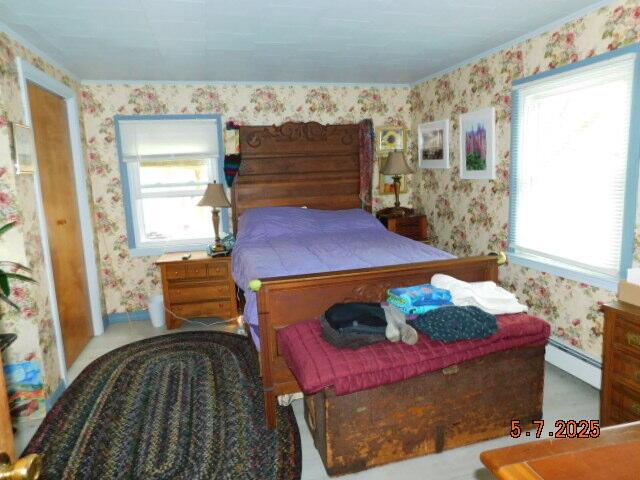 bedroom with wallpapered walls and a baseboard heating unit