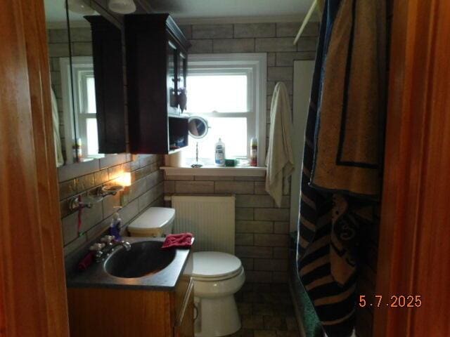 full bathroom featuring toilet, a shower with curtain, tile walls, and vanity