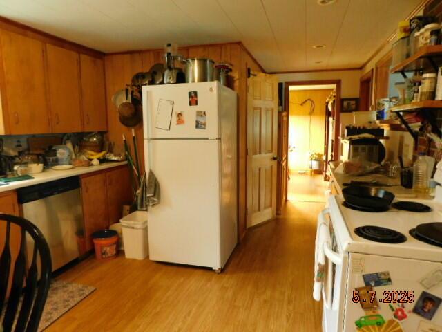 kitchen featuring white appliances, light wood-type flooring, brown cabinetry, and light countertops