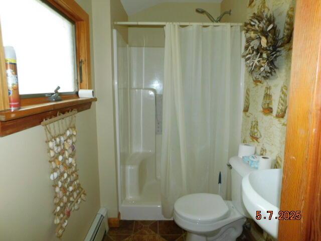 full bath featuring a shower stall, tile patterned floors, toilet, and baseboard heating