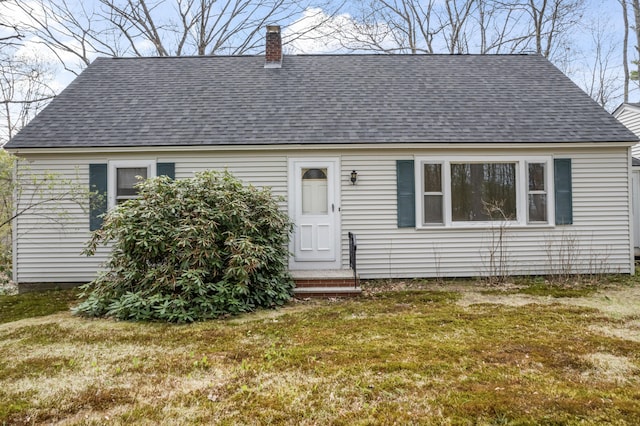view of front of house featuring a shingled roof, a front yard, and a chimney