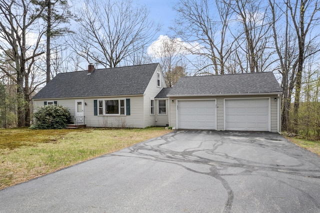 cape cod house featuring a garage, driveway, a chimney, a front lawn, and roof with shingles