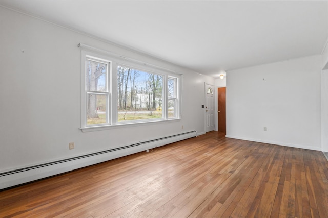 unfurnished living room featuring baseboard heating, hardwood / wood-style floors, and baseboards