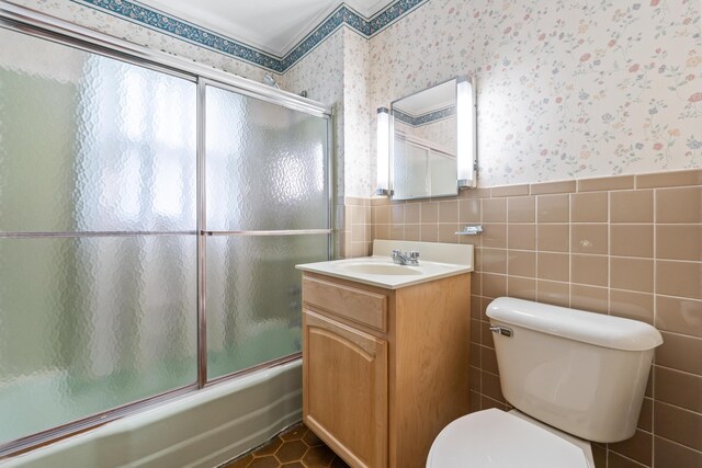 full bathroom with wallpapered walls, toilet, a wainscoted wall, tile walls, and enclosed tub / shower combo