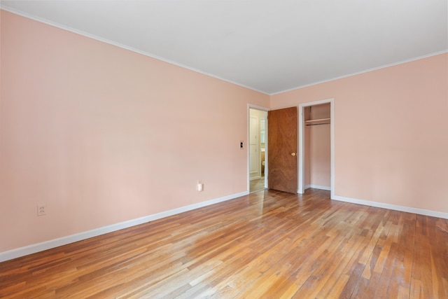 unfurnished bedroom featuring light wood finished floors, baseboards, a closet, and crown molding