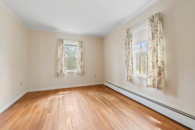 unfurnished room featuring a baseboard heating unit, crown molding, hardwood / wood-style floors, and baseboards