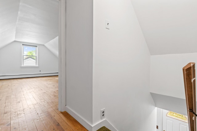bonus room with lofted ceiling, a baseboard heating unit, hardwood / wood-style flooring, and baseboards