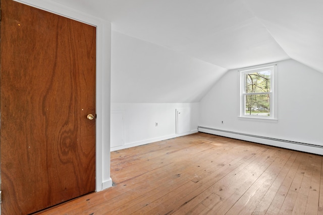 additional living space featuring a baseboard heating unit, lofted ceiling, and wood-type flooring