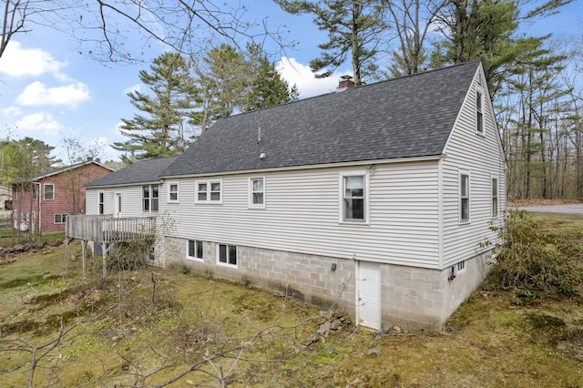 back of property featuring a shingled roof, a chimney, and a deck