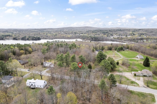 aerial view of property and surrounding area with a nearby body of water and a forest