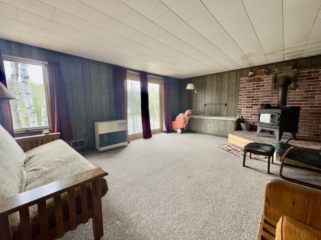 1429 Canada Rd, Moscow, ME 04920 - carpeted living area with a wood stove, plenty of natural light, heating unit, and wooden walls