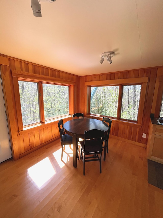 dining space with light wood-style floors and wooden walls