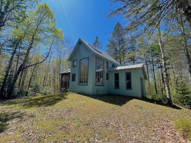 view of property exterior featuring metal roof and a lawn