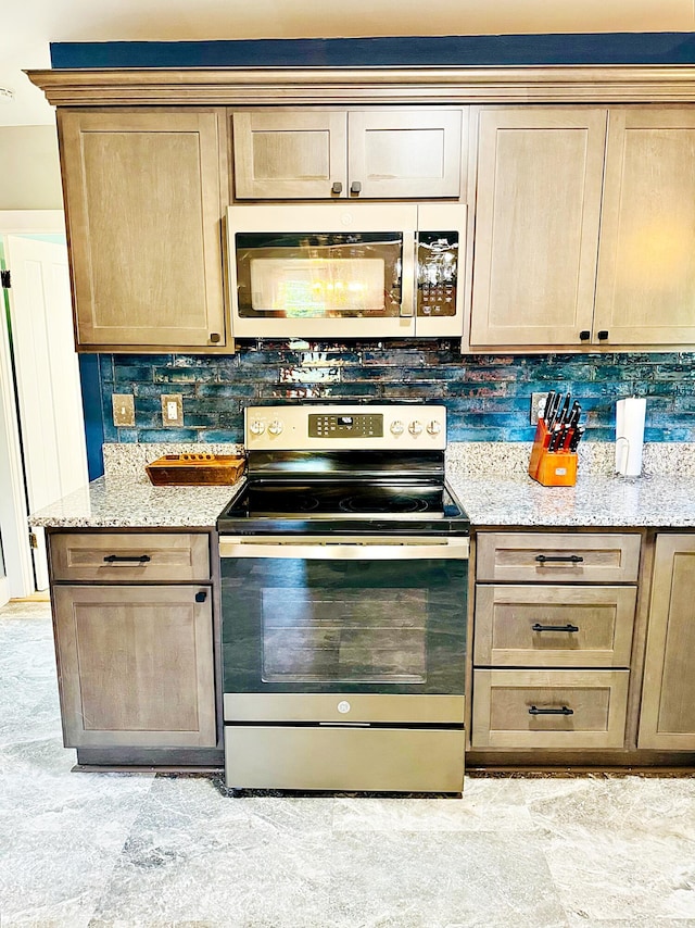 2 High St, Machias, ME 04654 - kitchen featuring stainless steel electric stove, white microwave, light stone countertops, decorative backsplash, and light brown cabinetry