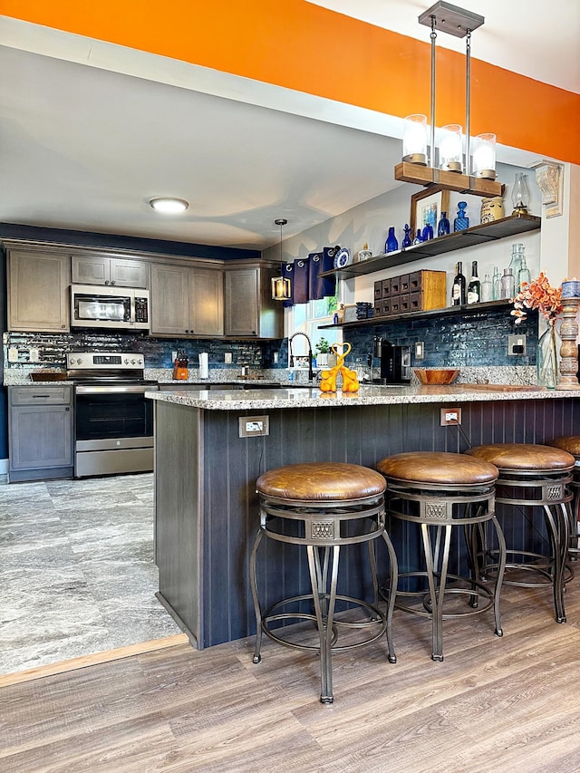 2 High St, Machias, ME 04654 - kitchen with appliances with stainless steel finishes, tasteful backsplash, open shelves, hanging light fixtures, and a breakfast bar
