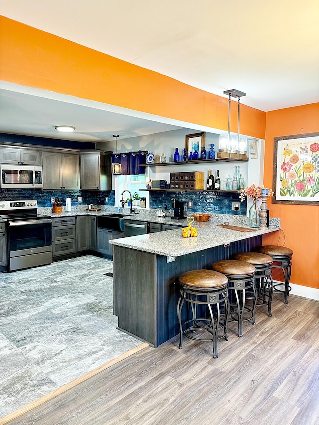 2 High St, Machias, ME 04654 - kitchen featuring stainless steel appliances, light wood-type flooring, a peninsula, decorative backsplash, and decorative light fixtures