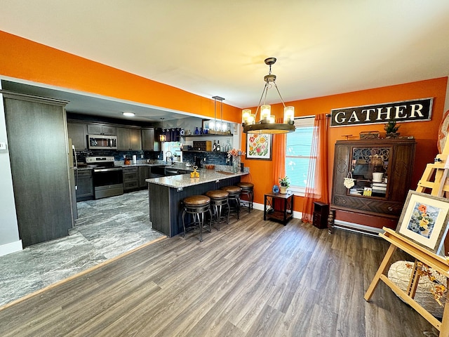 2 High St, Machias, ME 04654 - kitchen with appliances with stainless steel finishes, a peninsula, hanging light fixtures, a breakfast bar, and baseboards