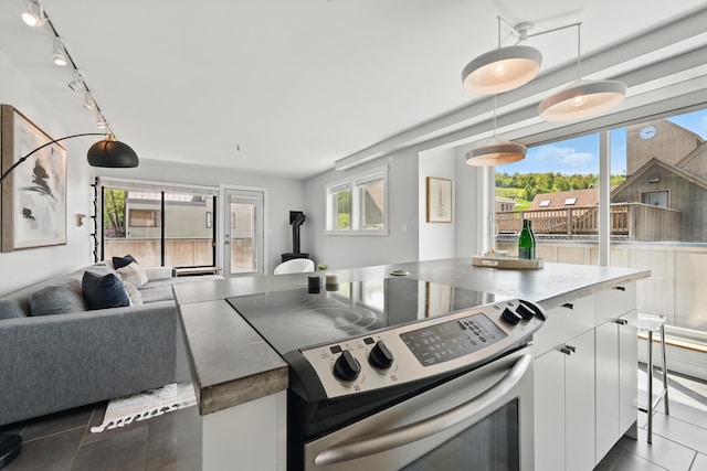 3027 Main St Unit 3027, Carrabassett Valley, ME 04947 - kitchen featuring stainless steel range with electric stovetop, dark tile patterned floors, white cabinets, open floor plan, and decorative light fixtures