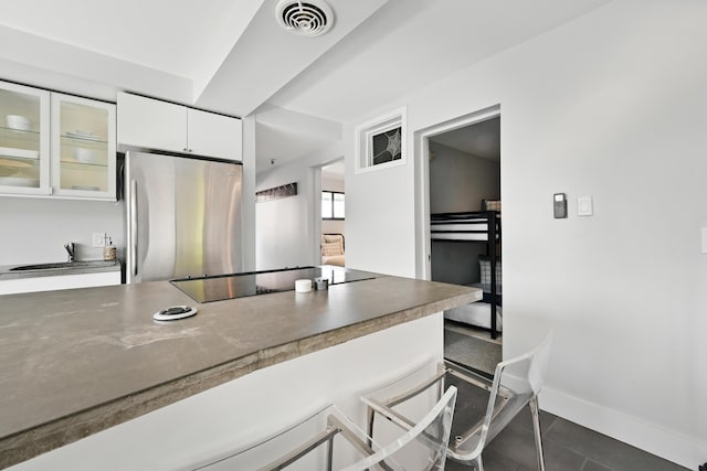3027 Main St Unit 3027, Carrabassett Valley, ME 04947 - kitchen featuring freestanding refrigerator, black electric cooktop, white cabinets, a kitchen breakfast bar, and glass insert cabinets