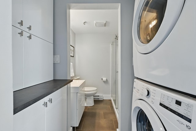 3027 Main St Unit 3027, Carrabassett Valley, ME 04947 - washroom featuring stacked washer / dryer, a baseboard radiator, baseboards, and dark tile patterned flooring