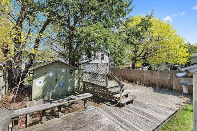 deck with a storage unit, a fenced backyard, and an outbuilding