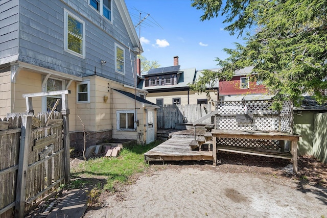 rear view of house featuring fence and a deck