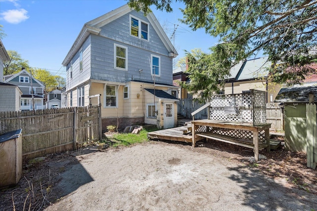 back of property with fence and a wooden deck