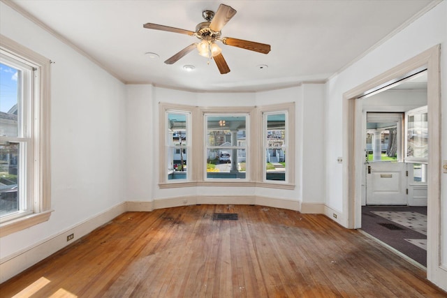 unfurnished room featuring hardwood / wood-style floors, healthy amount of natural light, ornamental molding, and baseboards