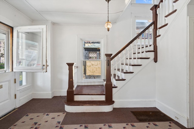 foyer entrance with stairs, healthy amount of natural light, baseboards, carpet, and crown molding