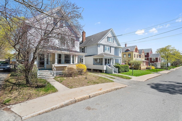 traditional style home with a chimney, a residential view, and a shingled roof