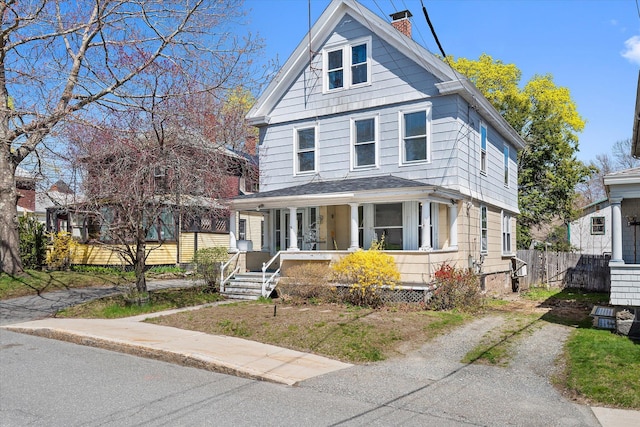 traditional style home featuring covered porch, a chimney, and fence