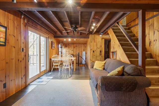 living area with wood walls, wood ceiling, beam ceiling, stairs, and carpet flooring