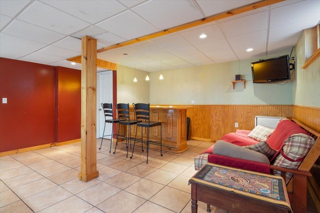 indoor dry bar with a wainscoted wall, tile patterned flooring, a paneled ceiling, wooden walls, and recessed lighting