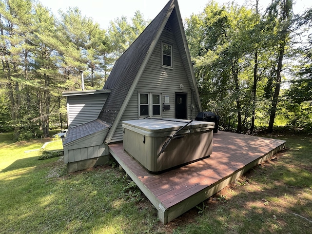 back of property featuring a hot tub, a deck, a yard, and roof with shingles