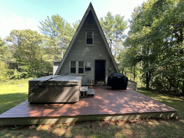 back of property with a hot tub, a deck, and a yard
