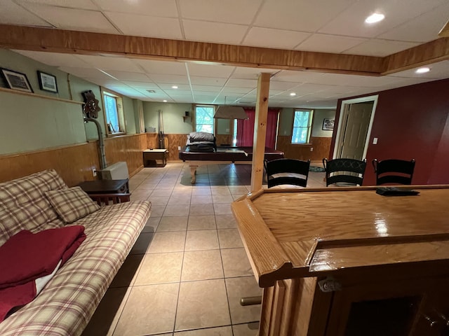tiled living area featuring a wainscoted wall, pool table, wood walls, and a drop ceiling