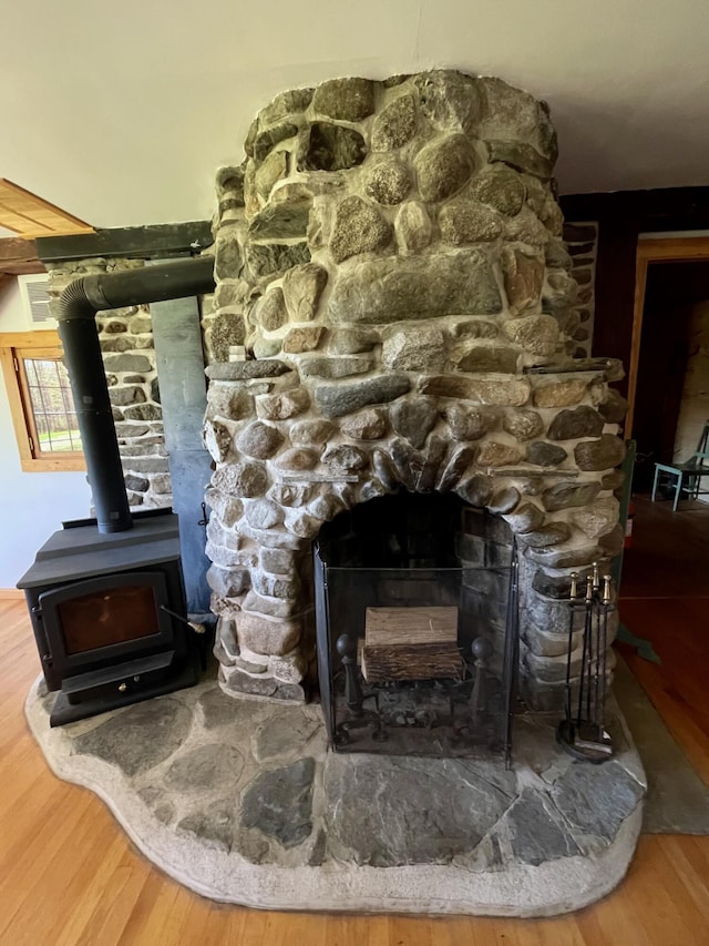 detailed view of wood finished floors, a wood stove, and a fireplace