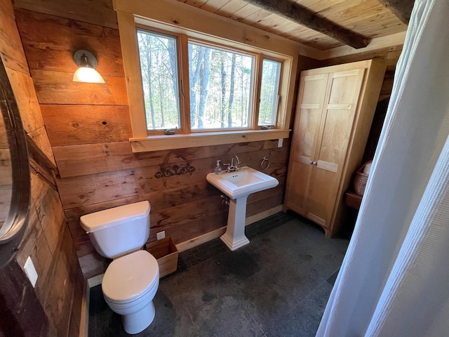 bathroom with wood ceiling, toilet, wood walls, and beamed ceiling