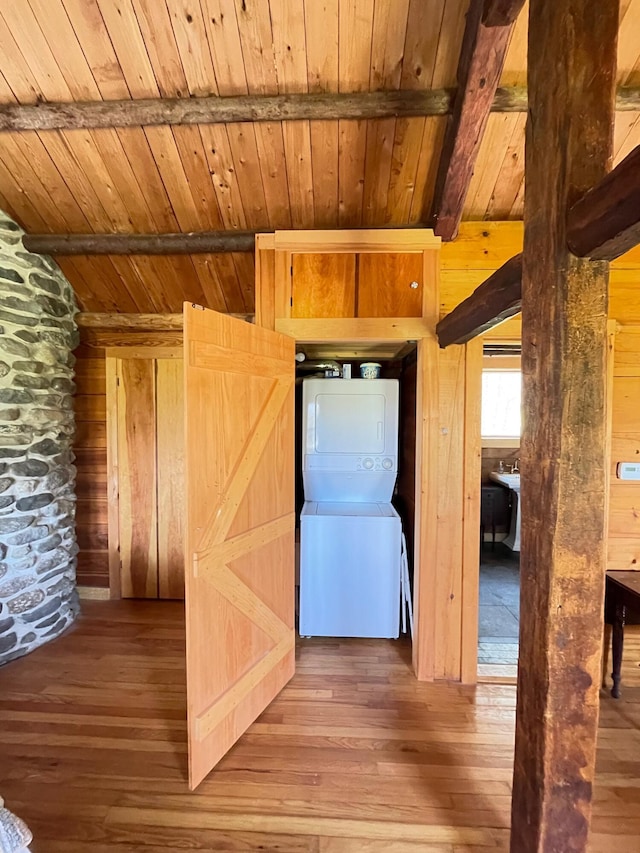 hall with estacked washer and dryer, wooden ceiling, wood-type flooring, and wood walls