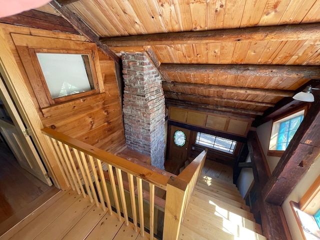stairs featuring wood ceiling, wooden walls, beamed ceiling, and hardwood / wood-style flooring