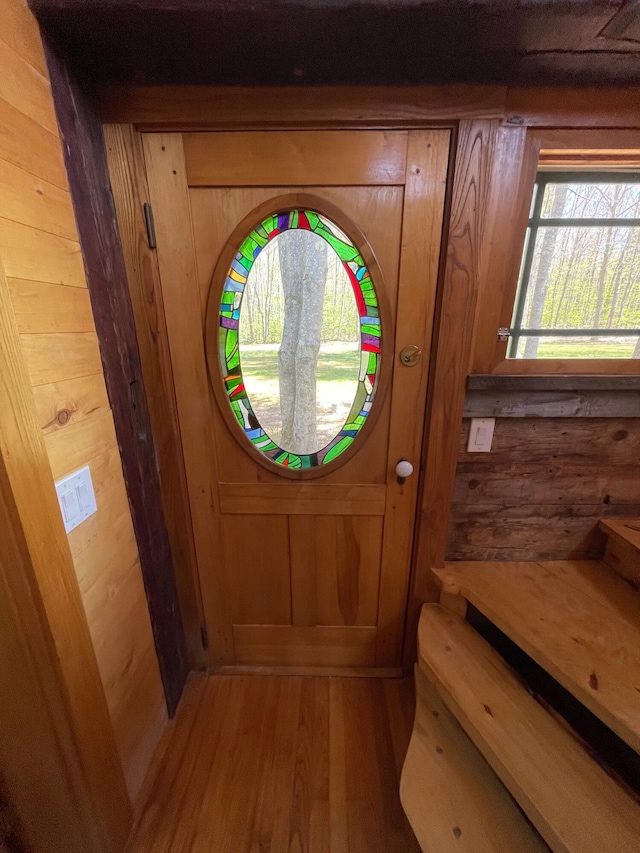 entryway with light wood finished floors and wooden walls