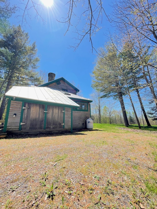 view of side of property featuring a chimney and a lawn