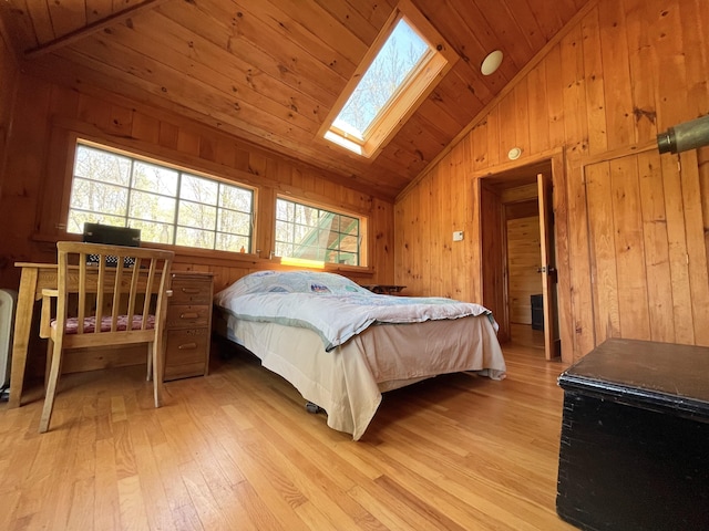 bedroom featuring vaulted ceiling, light wood-style floors, a skylight, multiple windows, and wooden walls