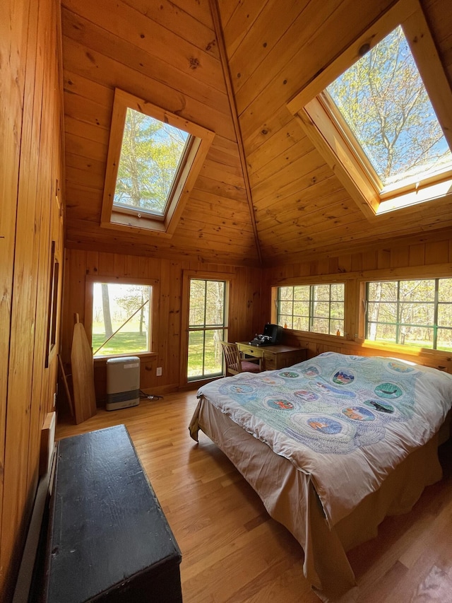 bedroom with a skylight, lofted ceiling, wooden walls, and light wood-style floors