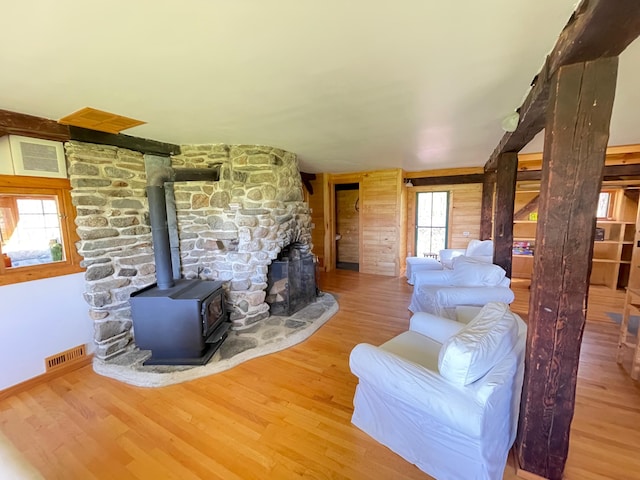 living area featuring wood finished floors, a wood stove, and baseboards