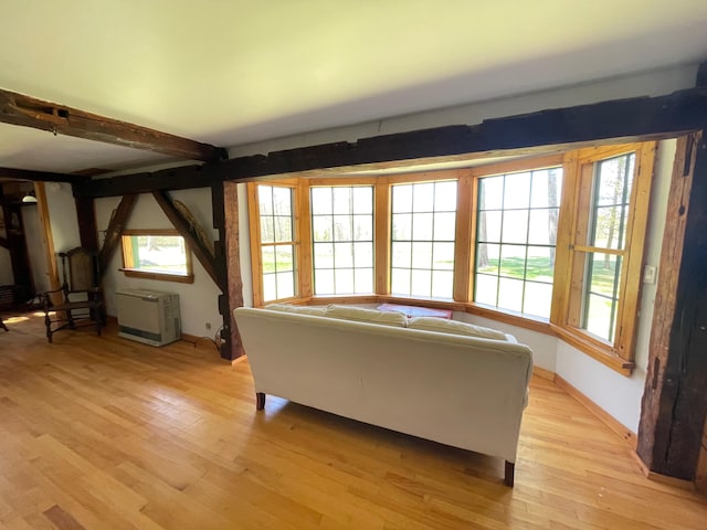 living area with light wood-style flooring, baseboards, and beam ceiling