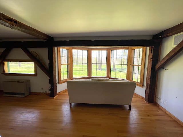 living area with light wood-style floors, beamed ceiling, and baseboards